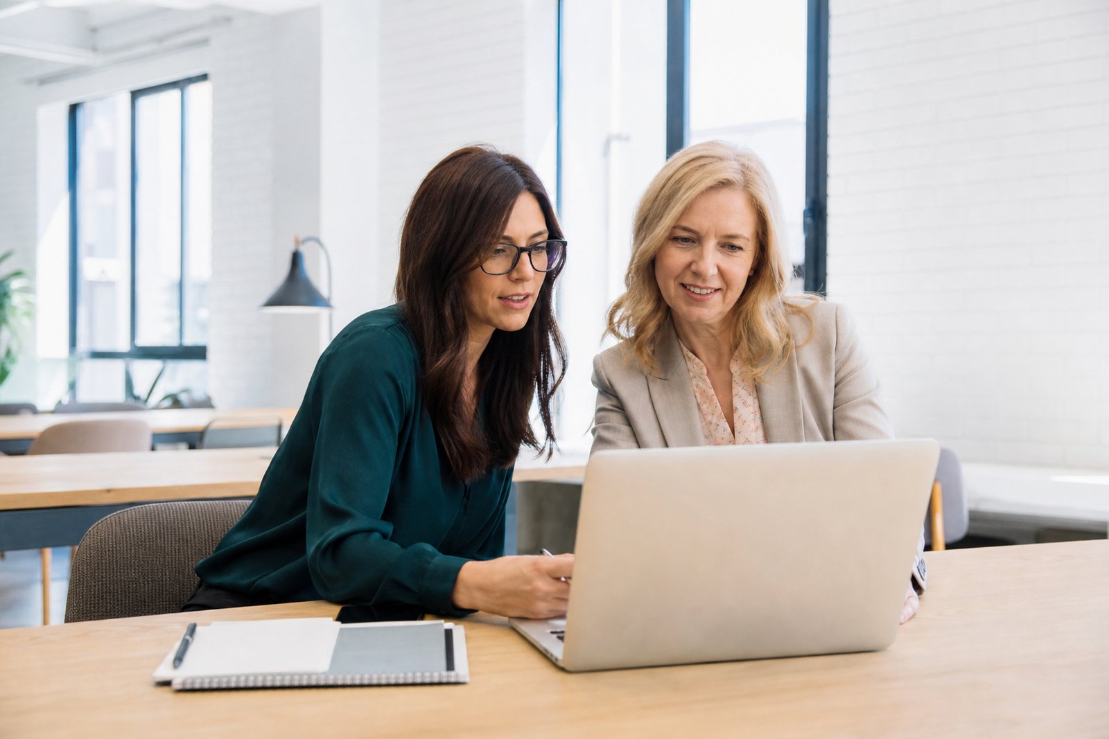 A career coach and a client in her forties reviewing a resume on a laptop in a bright coworking space